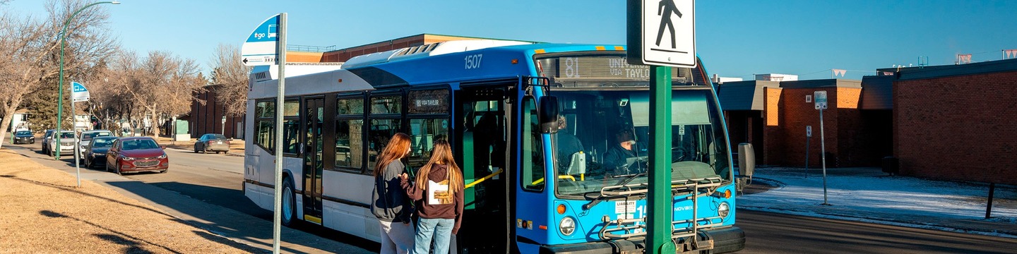 Two people standing at a bus stop, about to get on a bus.